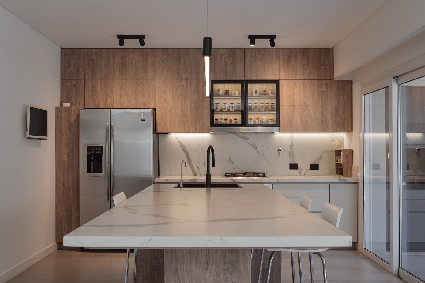 Cocina terminada tras la ejecución de la obra, con isla de mármol y carpintería de madera